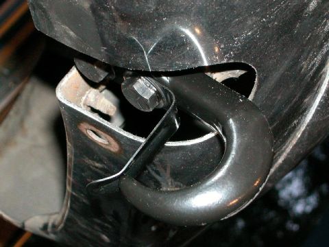 1995 Ford Bronco - Close-up of a black steel tow hook bolted to a vehicle frame, secured with a hex bolt and a black metal safety retainer clip. The mounting…