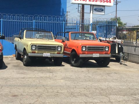 1968 Ford Mustang - Two vintage International Harvester Scouts are parked in front of a blue fence.