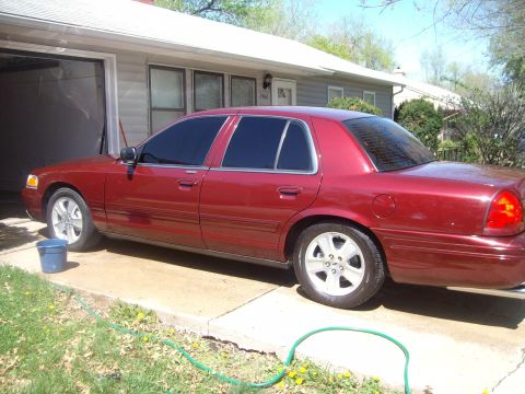 2004 Ford Crown Victoria - A red 2004 Ford Crown Victoria is parked in a driveway next to a garage.