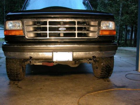 1995 Ford Bronco - Front view of a black Ford SUV with a chrome-accented grille bearing the Ford oval, dual round headlights and amber turn signals, and a bla…