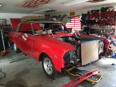 1964 Ford Fairlane - A red coupe is in a garage with its hood up and front end partially dismantled for repairs.