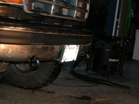 1995 Ford Bronco - Low night flash shot of the front of a Ford truck showing the chrome grille, chrome bumper, and a mud-terrain tire; a Craftsman shop vacuum…