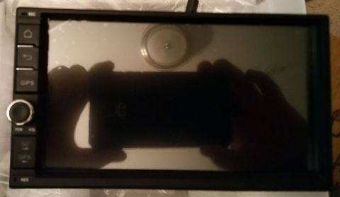 2001 Ford Excursion - A car stereo head unit is shown, with several buttons and a large screen reflecting a circular object.
