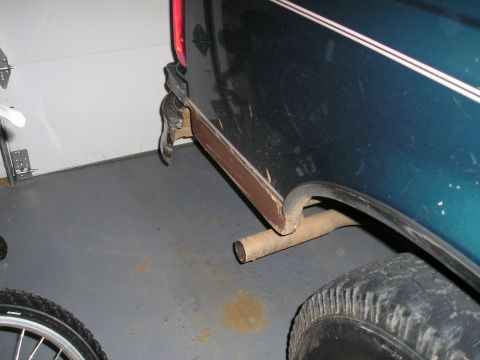 1996 Ford Bronco - Close-up of a vehicle's rear fender and exhaust pipe, with visible rust on the trim.