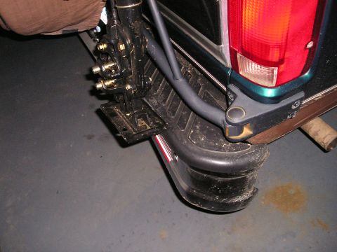 1996 Ford Bronco - A jack is mounted to the rear of a vehicle, near the tailgate and taillight assembly.