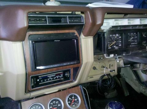 1982 Ford Bronco - The interior of a vehicle dashboard shows a Pioneer stereo, an aftermarket radio, and various gauges. The dashboard is brown and tan with w…
