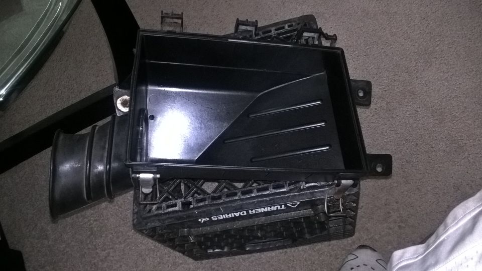 Black plastic air intake box with hose attachment on milk crate