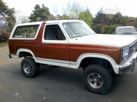1982 Ford Bronco - This lifted 1980s Ford Bronco features a two-tone paint scheme and is shown from the side.