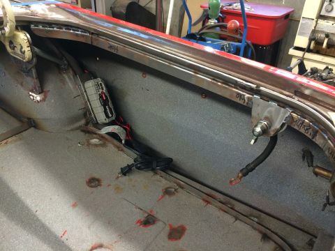 1964 Ford Fairlane - The interior of a car trunk shows metalwork and a battery charger, with no clear year identification.