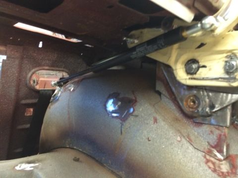 1964 Ford Fairlane - Close-up view of the interior wheel well area, showing suspension components and metalwork. Some red staining is present on the metal surfa…