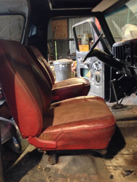 1979 Ford Bronco - Interior view of a vehicle with red seats and exposed door frame, suggesting a restoration project.