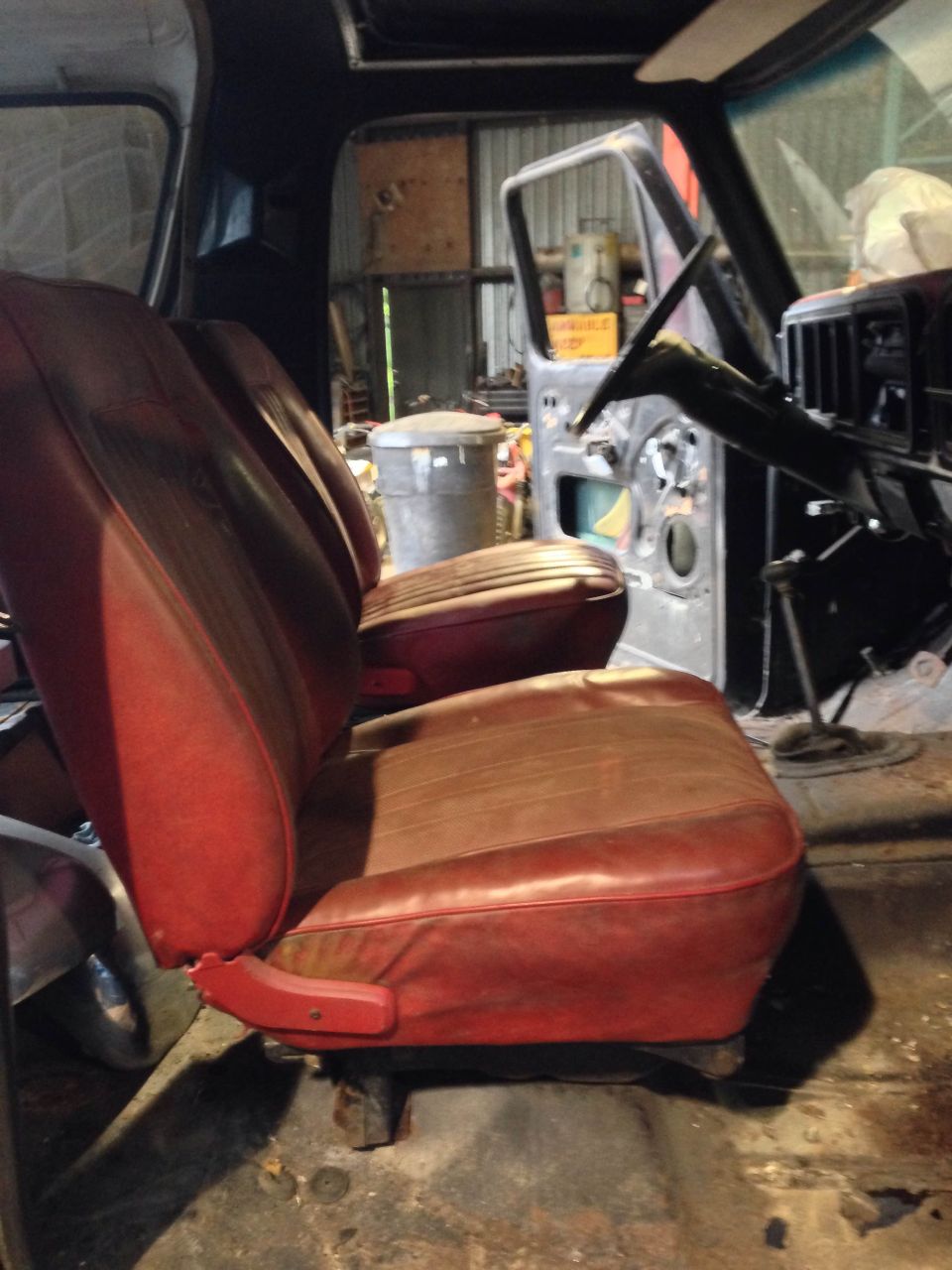 Red bucket seats inside a disassembled vehicle, showing the steering wheel and open door