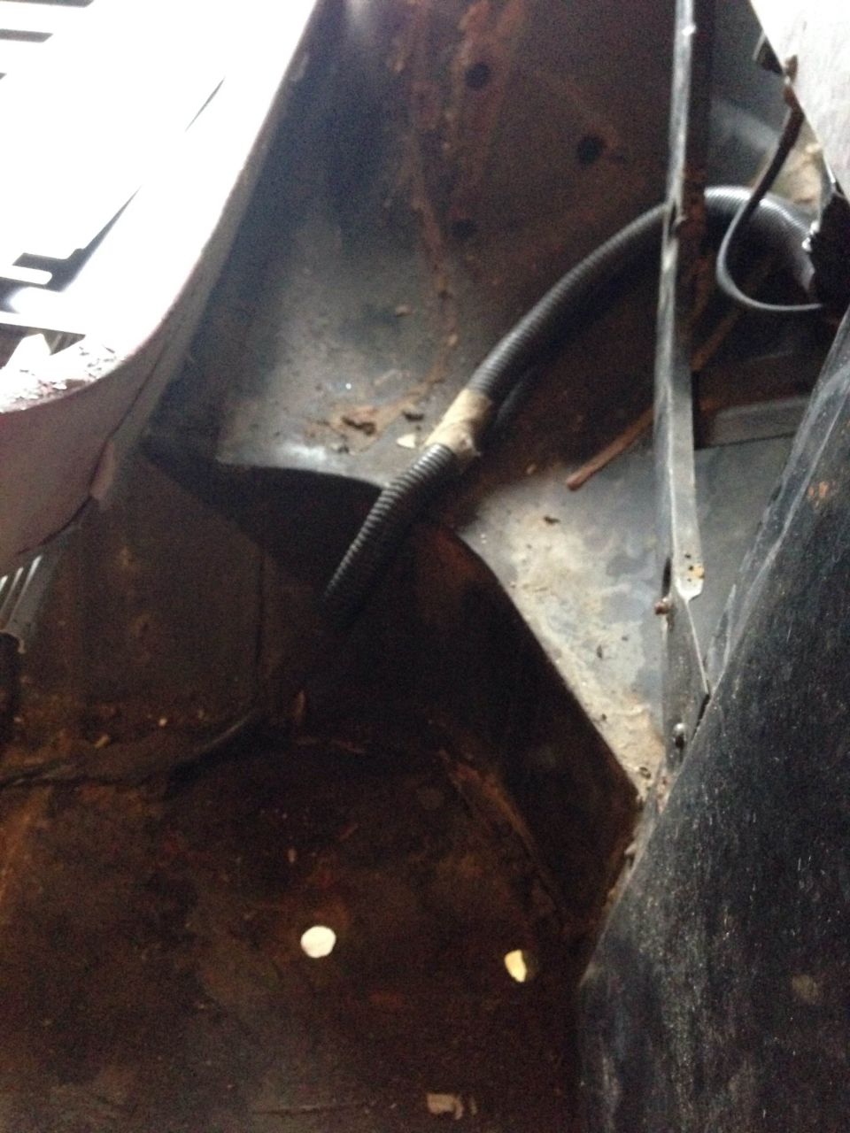 Interior fender well with rust and a black hose