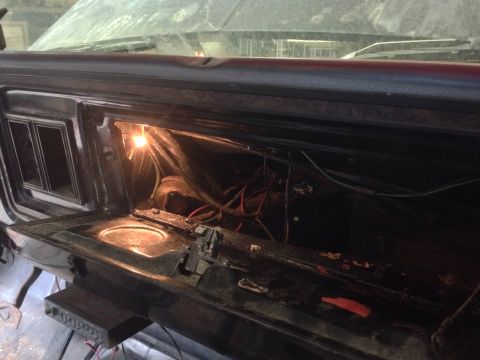 1979 Ford Bronco - The interior of a vehicle shows an open glove compartment with exposed wiring and a lit bulb.
