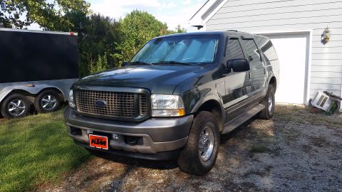2003 Ford Excursion - This 2003 Ford Excursion is parked in front of a garage with a trailer to its left.