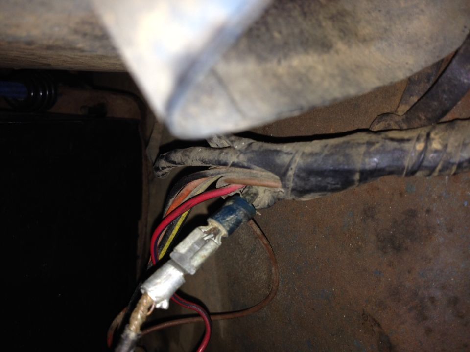 Underbody close-up of frayed wiring harness with exposed red and brown wires and a spade connector on a 1973 Ford Bronco