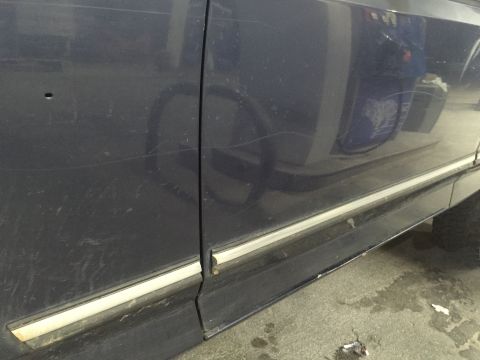 1993 Ford Bronco - Close-up view of the side of a dark blue vehicle, showing door panel and trim details.