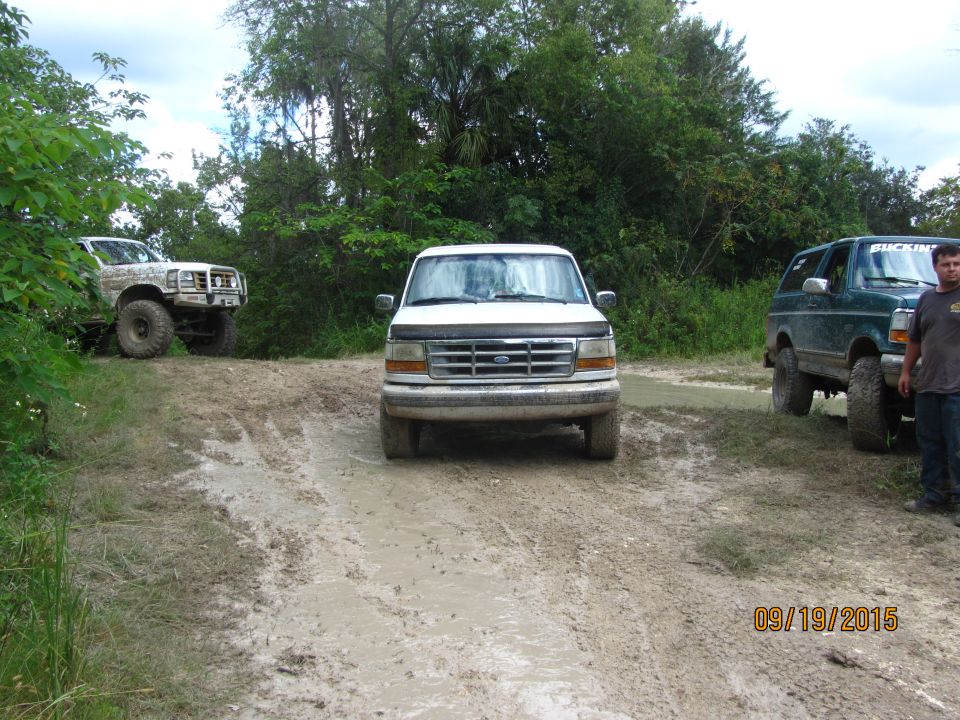 White 1992 Ford F-Series truck on a muddy road, front view