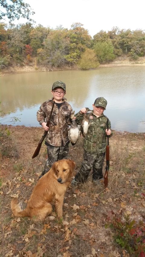 1993 Ford Bronco - Two boys and a dog pose with their hunting gear and ducks by a calm lake surrounded by autumn trees.