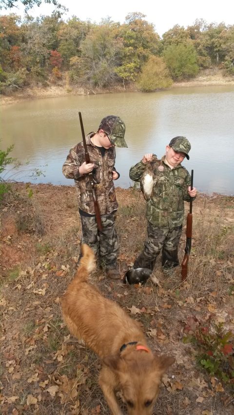 1993 Ford Bronco - Two young hunters pose with their dog and duck catch near a body of water, with autumn foliage in the background.