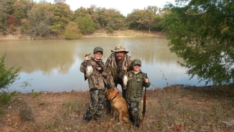 1993 Ford Bronco - A successful hunting trip by the water, with a family and their dog posing with their catch.