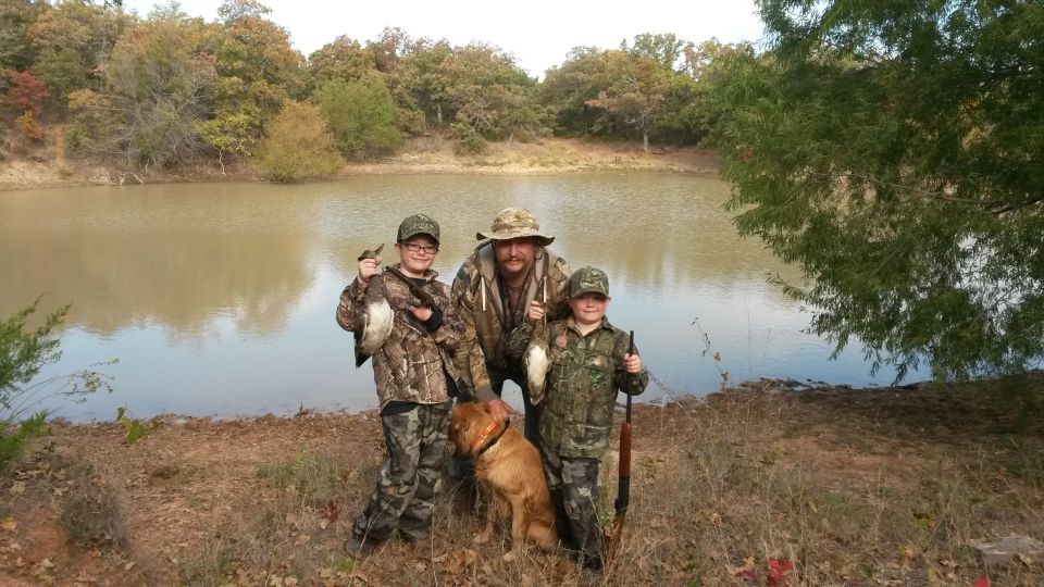 Family by lake with hunting gear and ducks