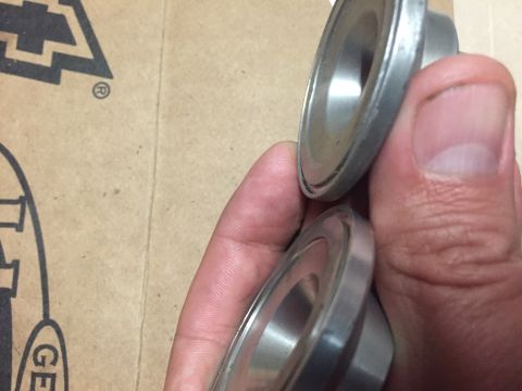 1988 Ford Bronco - Close-up of two metal valve seats being held in a hand.