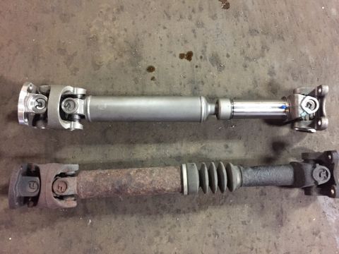 1995 Ford Bronco - Comparison of a new driveshaft next to an old, rusted one with a rubber boot.