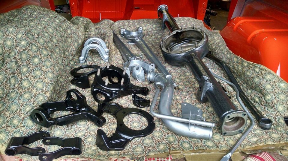 Various black and silver vehicle suspension and axle components laid out on a patterned cloth