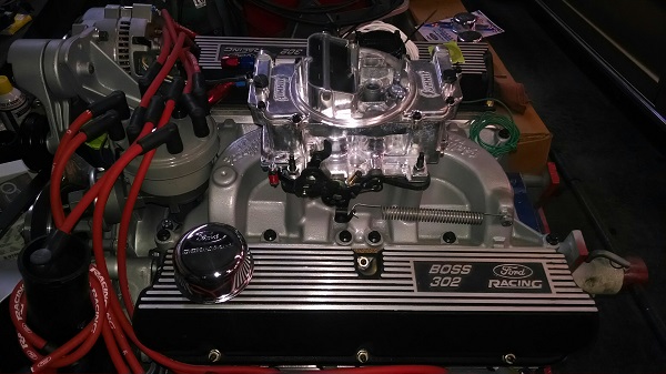Ford Boss 302 engine valve covers, carburetor, and distributor with red spark plug wires