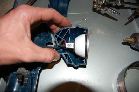 1994 Ford Bronco - A person's hand holds a blue plastic housing with a white light fixture inside. The housing appears to be part of a tool or appliance, not…