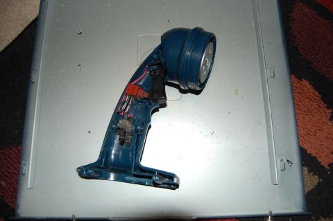1994 Ford Bronco - A disassembled blue flashlight is shown resting on a metallic surface. The flashlight's internal components, including wires and a switch,…