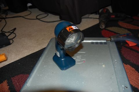 1994 Ford Bronco - A blue cordless work light with LED bulbs sits on top of a silver metal case. In the background, a hot glue gun and a heat gun are visible…