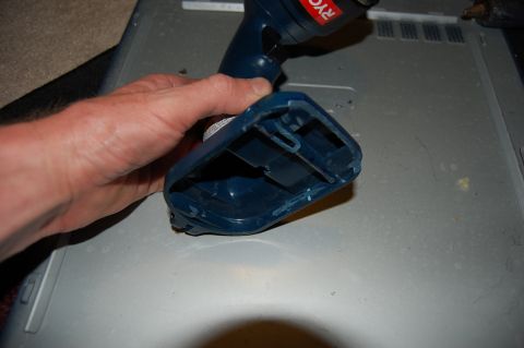 1994 Ford Bronco - A hand holds a blue power tool with a "RYOBI" logo over a gray surface. The tool appears to be a drill with a battery pack attached.