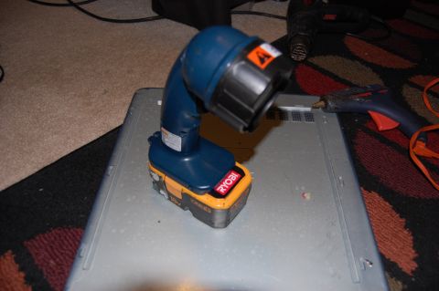 1994 Ford Bronco - A blue and yellow Ryobi work light is attached to a battery pack and is sitting on top of a gray metal object. A blue and orange hot glue g…