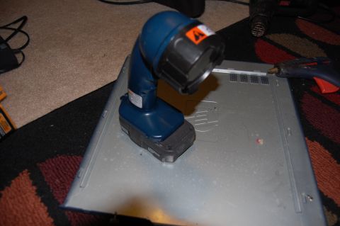 1994 Ford Bronco - A blue cordless work light with a battery pack is placed on top of a gray metallic surface, possibly the lid of a computer or electronic de…