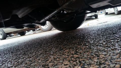1991 Ford LTD Crown Victoria - Photograph taken from beneath a car showing the undercarriage and exhaust over asphalt, not a technical document.