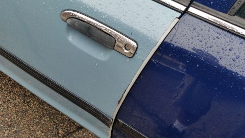 1991 Ford LTD Crown Victoria - Photograph of a chrome door handle and the two-tone paint break on a rain-covered car, not a technical document.