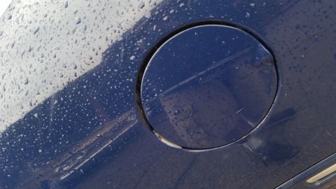 1991 Ford LTD Crown Victoria - Photograph of a circular fuel filler door on a rain-covered blue panel, not a technical document.