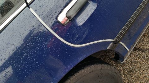 1991 Ford LTD Crown Victoria - Photograph of the two-tone paint break, door handle, and rear wheel arch on a rain-covered car, not a technical document.