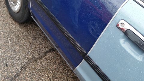1991 Ford LTD Crown Victoria - Photograph of the lower rocker, door edge, and front wheel of a two-tone car in the rain, not a technical document.