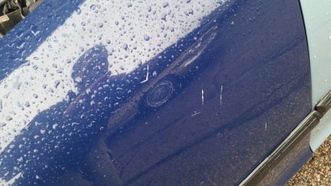 1991 Ford LTD Crown Victoria - Photograph of a blue door panel with a lock cylinder and surface scratches in the rain, not a technical document.