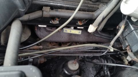 1991 Ford LTD Crown Victoria - Photograph of an engine valve cover, plug wires, and an Engine Oil label inside an engine bay, not a technical document.