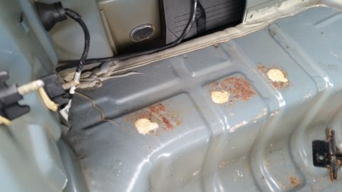 1991 Ford LTD Crown Victoria - Photo of a vehicle trunk floor with rust spots and wiring, not a technical document.