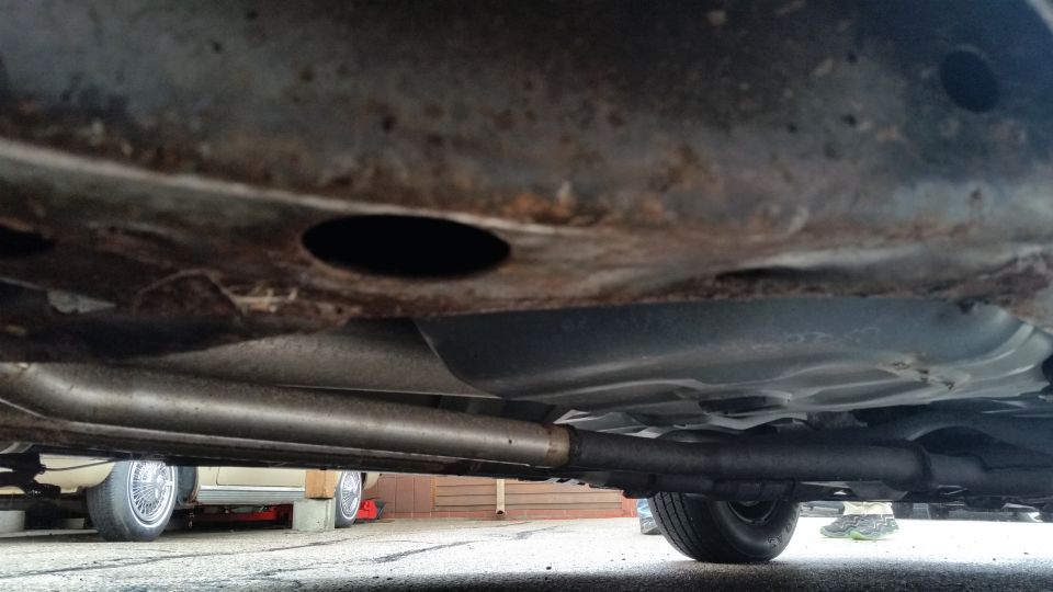 Underbody view of rusty frame, exhaust and fuel tank