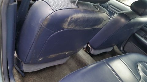 1991 Ford LTD Crown Victoria - Photograph of a vehicle's worn blue leather rear seatback and center console, not a technical document.