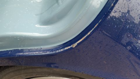 1991 Ford LTD Crown Victoria - Close-up photo of a vehicle body panel gap showing two-tone blue paint and minor rust, not a document.