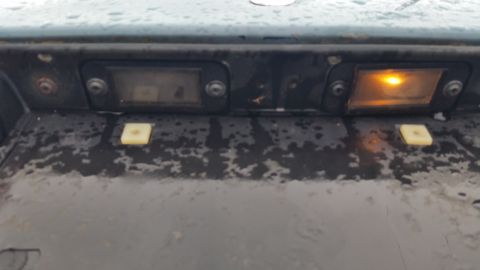 1991 Ford LTD Crown Victoria - Photo of a vehicle's rear license-plate lamp panel with one bulb lit, not a technical document.