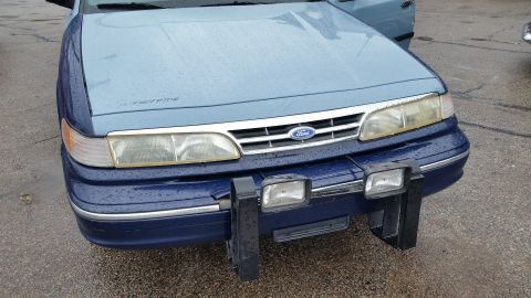 1991 Ford LTD Crown Victoria - Photograph of the front end of a two-tone blue Ford sedan with a push bumper, not a document.