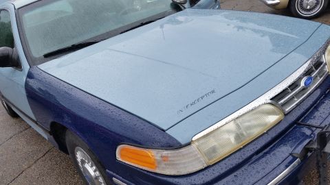 1991 Ford LTD Crown Victoria - Photo of the wet hood and fender of a two-tone blue Ford Police Interceptor, not a document.